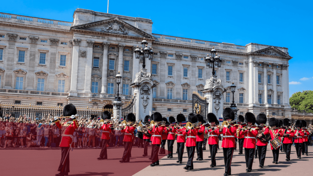Buckingham Palace mit Marschkapelle der Garde im roten Rock und Bärenfellmütze.