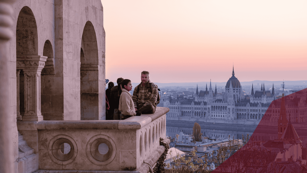 Paar auf Balkon mit Blick auf Parlamentsgebäude bei Sonnenuntergang