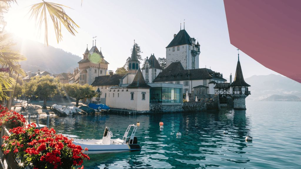 Schloss auf einer Insel im See, mit Booten und Palmen im Vordergrund.