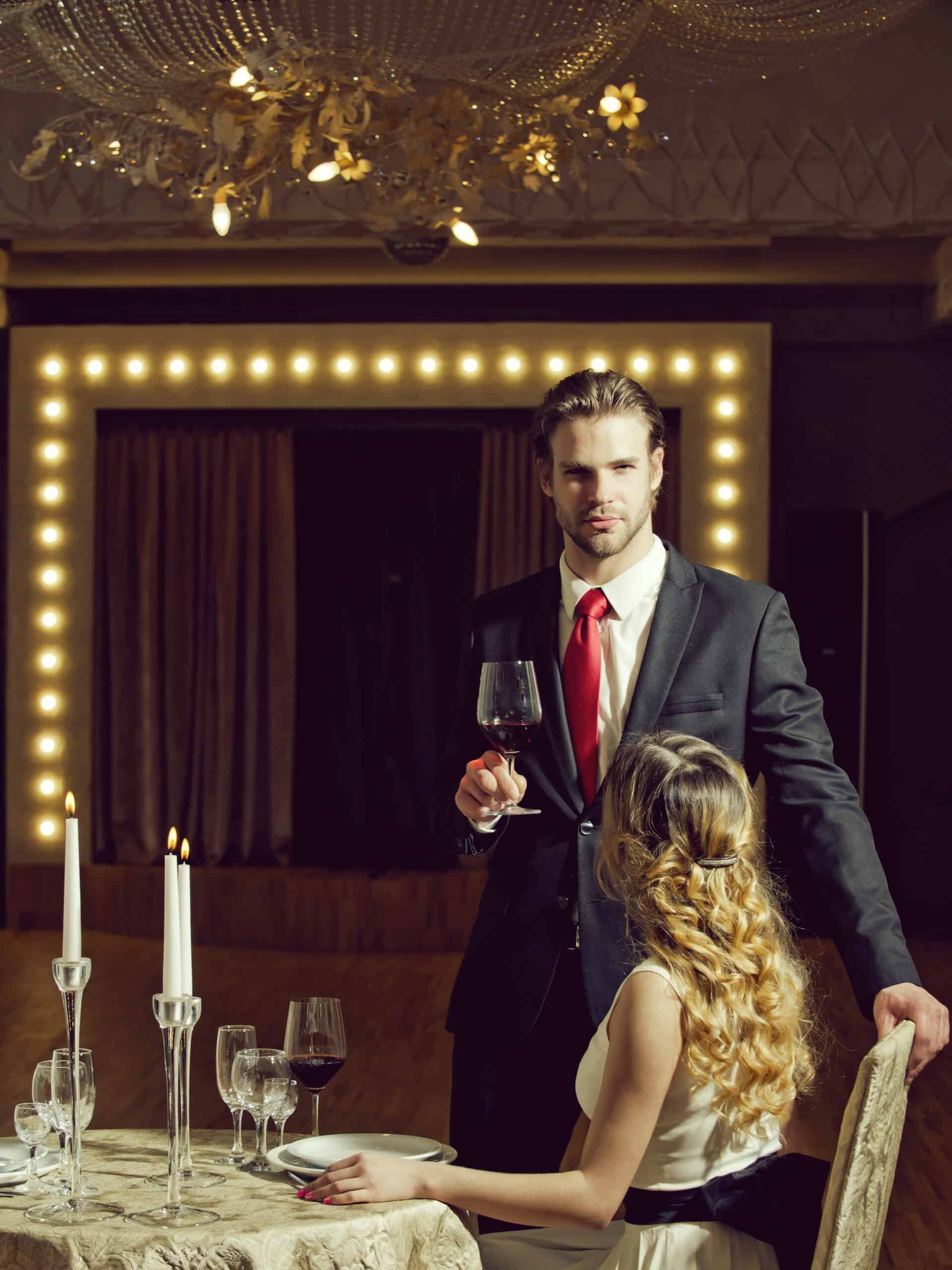 Mann in Anzug mit Rotwein, Frau im Abendkleid am Tisch
